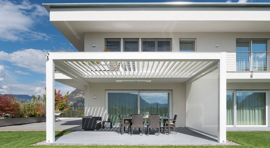 Lamellendach über sonniger Terrasse an einem modernen Wohnhaus